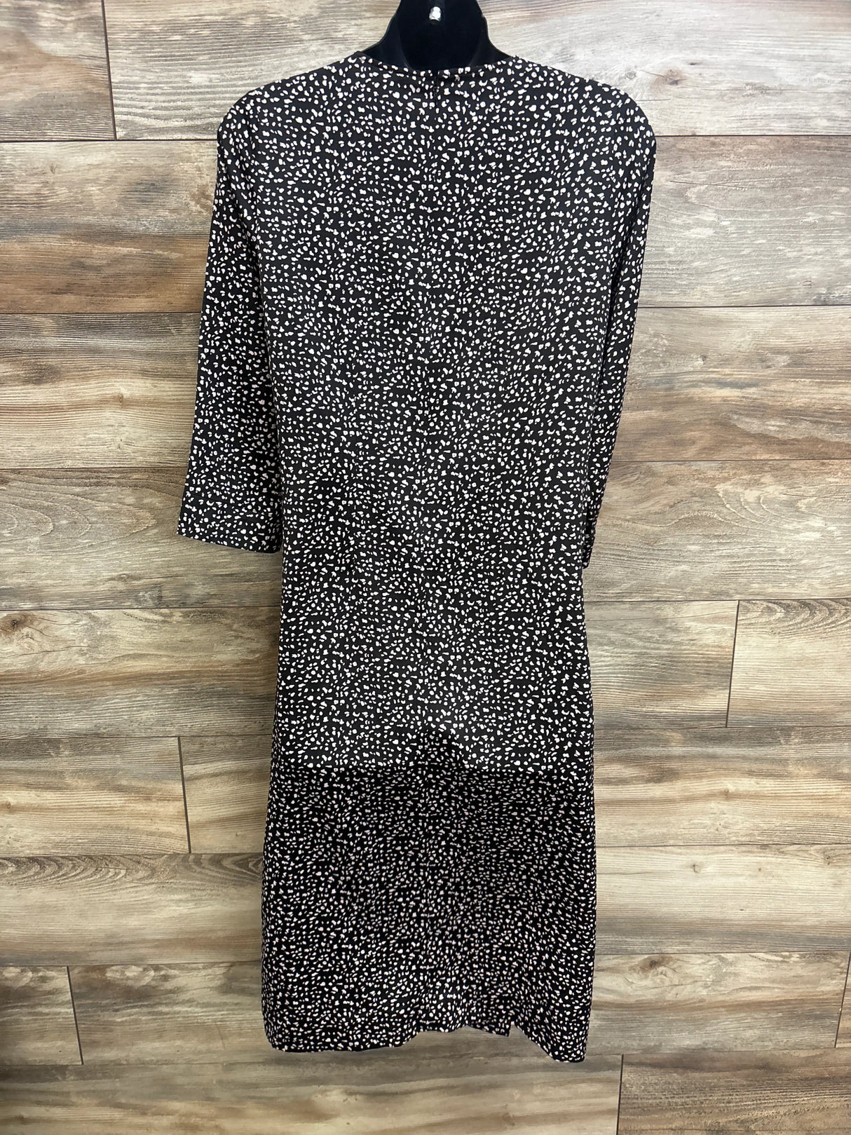 Back view of Hatch Maternity The Lauren dress in black, white speckled print, knee-length, on mannequin with wood background