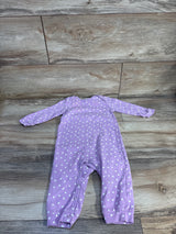 Front flat-lay of purple Care Bears coverall showcasing white heart print, long sleeves, and leg snap closures on wood floor background