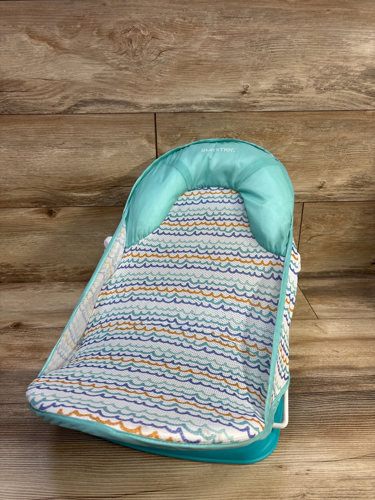 Front view of Summer Deluxe Baby Bather in green showcasing wavy patterned fabric on a wood floor