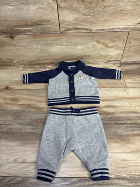 Gray and navy baby outfit set with striped trim on wood floor