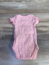 Flat lay of Simple Joys pink preemie bodysuit showing white polka dot pattern and short ruffled sleeves on wood background