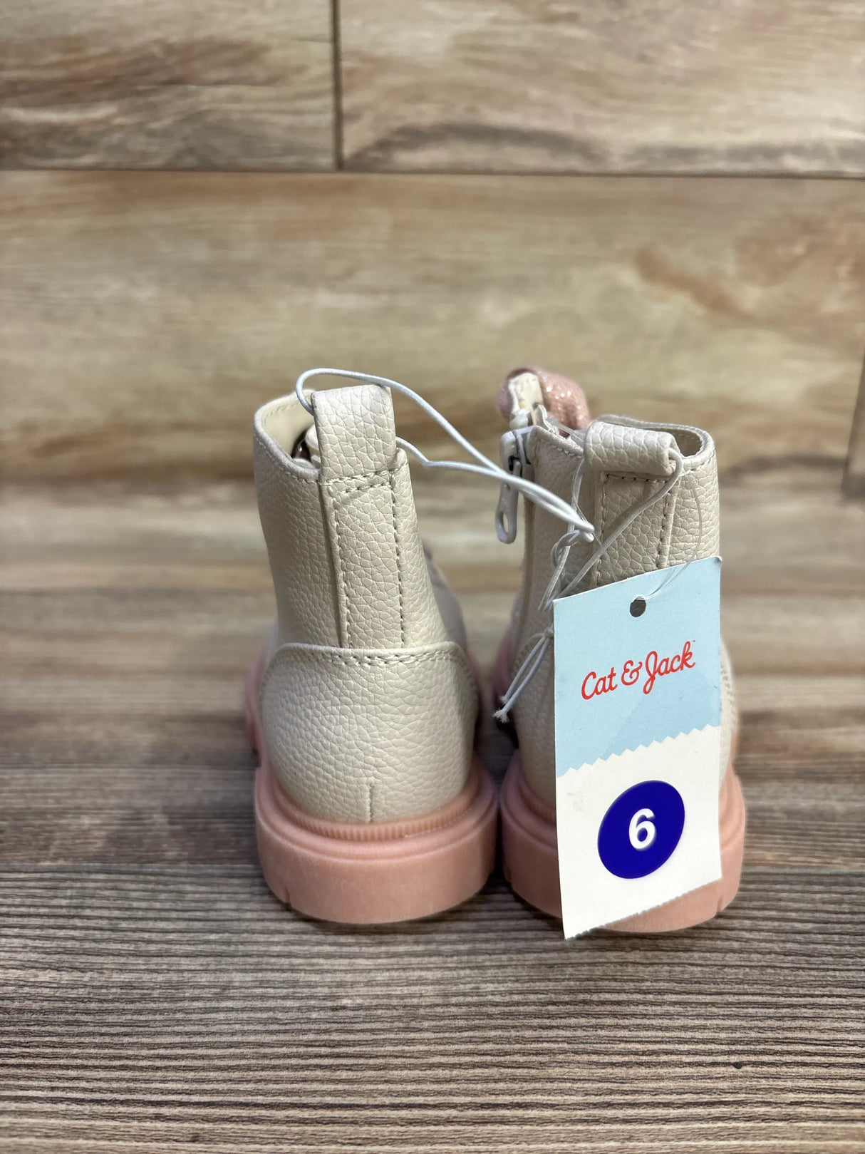 Rear of Cat & Jack Amaya zipper combat boots, pale pink with pink sole and size 6 tag on wood background