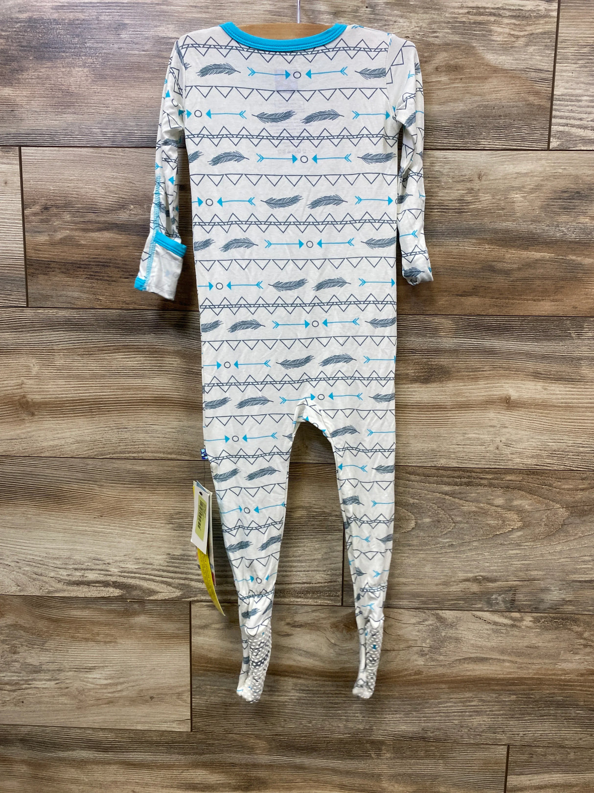Long sleeve baby sleeper with geometric and feather print, blue trim, displayed on wood background