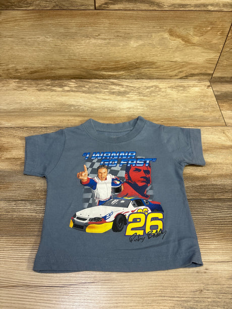 Front view of blue Talladega Nights Ricky Bobby shirt with race car 26 graphic and I Wanna Go Fast text on wood background