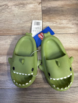 Top-down view of green Crayon Friends shark toddler slides showing shark face with white teeth and black eyes on wood floor