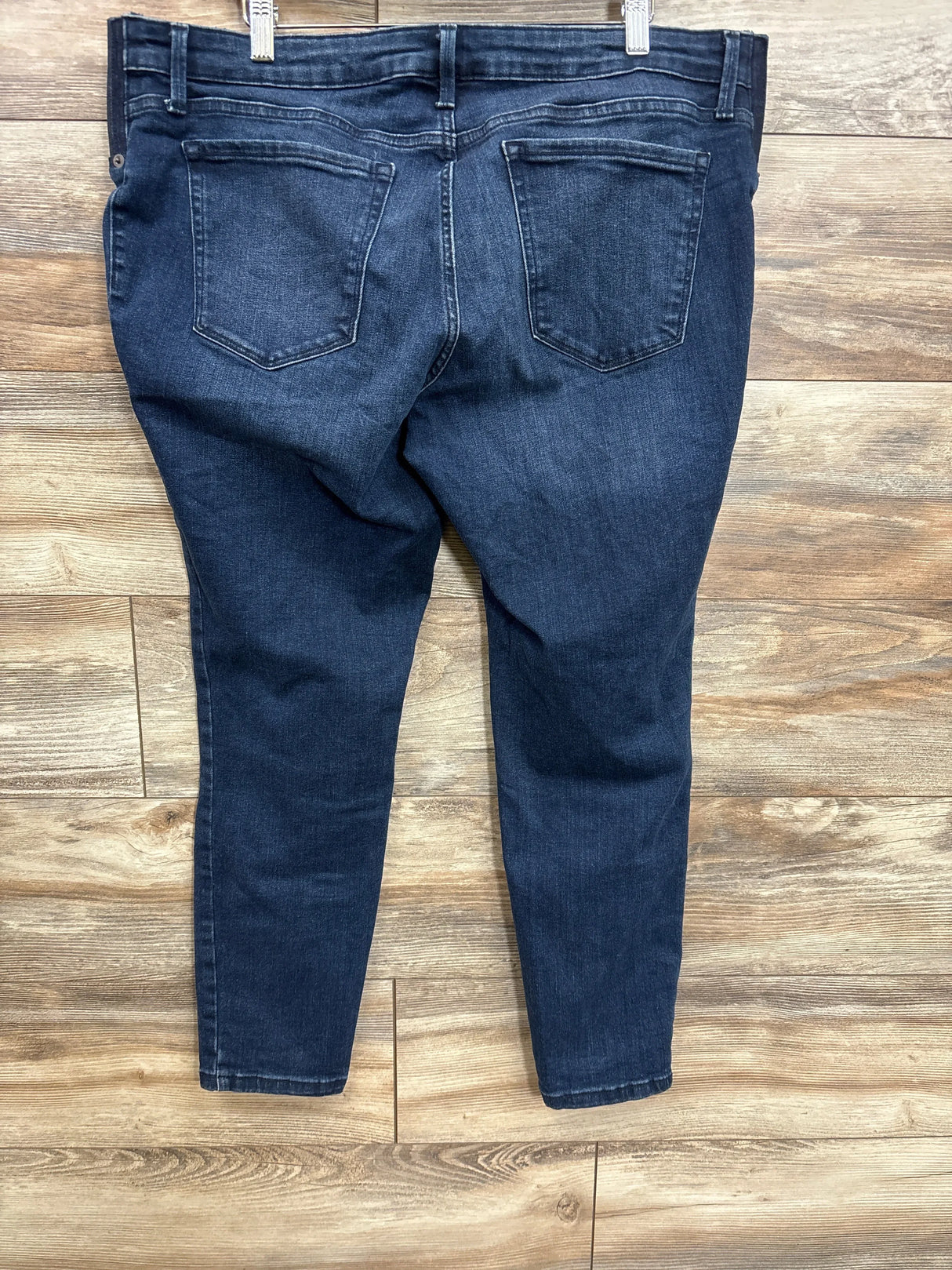 Back view of Isabel maternity side-panel denim skinny jeans showing back pockets and tapered legs on wood floor