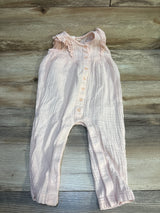Pink baby romper with ruffled sleeves and button front on wood background
