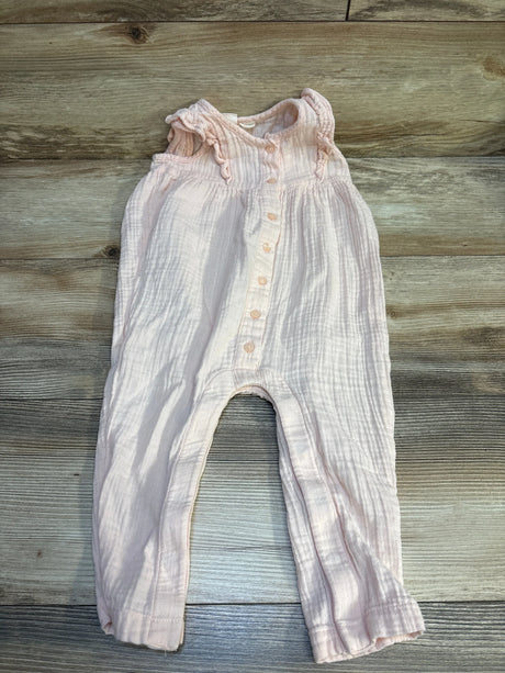 Pink baby romper with ruffled sleeves and button front on wood background