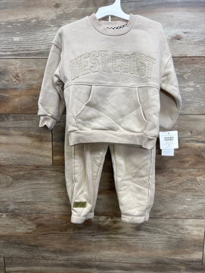 Front view of beige fleece crewneck and jogger set with WEST COAST applique, on white hanger against wood background