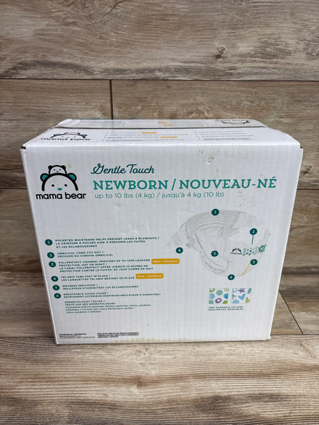 Front view of Mama Bear Gentle Touch newborn diapers package with umbilical cord cutout and leak protection on wood surface