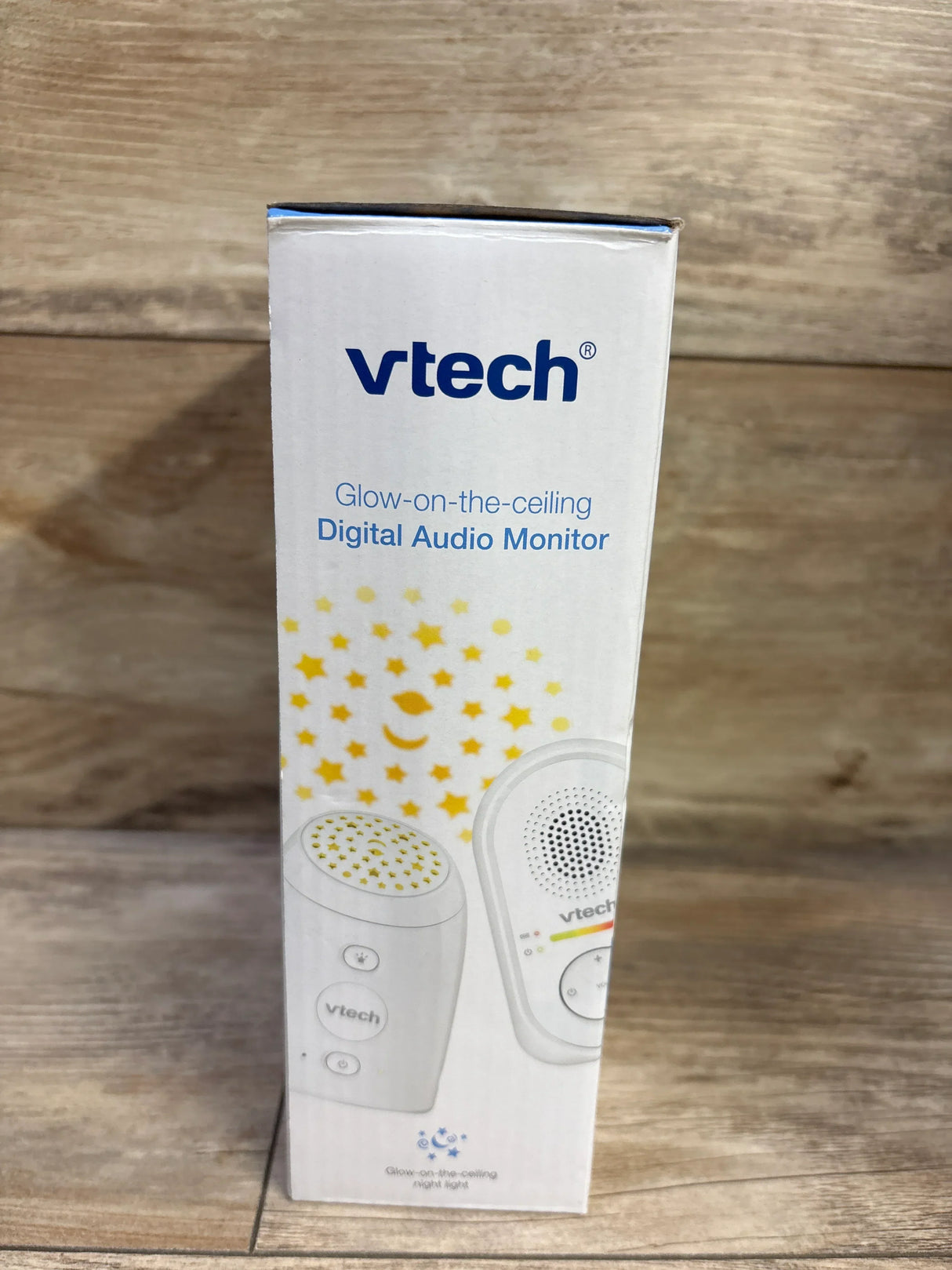 Front view of VTech Glow-on-the-Ceiling baby monitor box showing star-projection night-light graphic on wooden background
