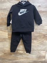 Front view of black Nike toddler hoodie and joggers set showing camo Nike swoosh on hoodie with wood floor background