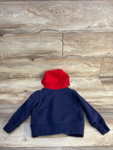 Navy blue kids hoodie with red hood, laid on wooden floor