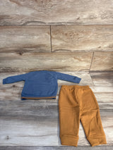 Blue long sleeve baby shirt and brown pants on wood floor background