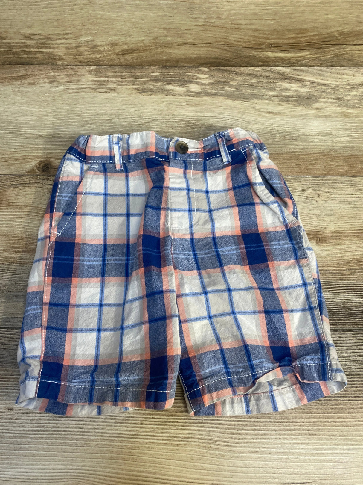 Boys plaid shorts in blue, red, and white on a wood background