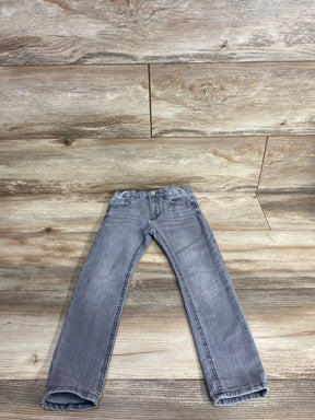 Gray kids jeans with pockets laid flat on wooden floor background