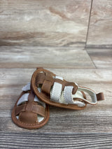 Front view of Cat and Jack tan baby sandals size 3C showing white elastic straps and stitched faux leather upper on wood
