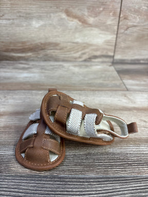 Front view of Cat and Jack tan baby sandals size 3C showing white elastic straps and stitched faux leather upper on wood