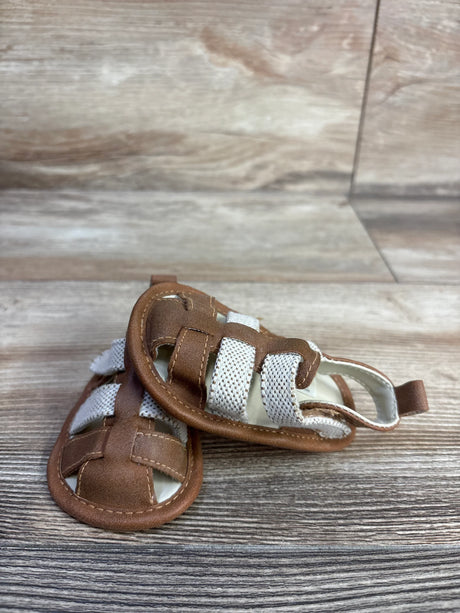 Front view of Cat and Jack tan baby sandals size 3C showing white elastic straps and stitched faux leather upper on wood