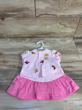 Flat lay of Bearpaw 2-piece embroidered polo and skort set in light pink showcasing multicolor butterfly embroidery on wood background
