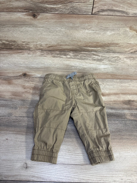 Flat lay of tan Carter's pull-on poplin pants size 6M showing elastic waistband with gray tie and elastic cuffs on wood