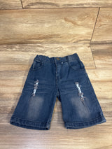 Front view of size 2T blue distressed denim toddler shorts showing ripped knee details and elastic waistband on wood floor background