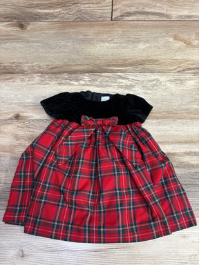Red plaid baby dress with black velvet top and bow, laid on wooden background