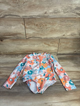 Flat lay of toddler long-sleeve floral rashguard one-piece swimsuit with front zipper and ruffle leg trim on wood background