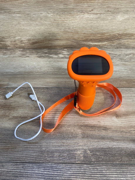 Orange kids toy camera with screen, lanyard, and USB charging cable on wood background