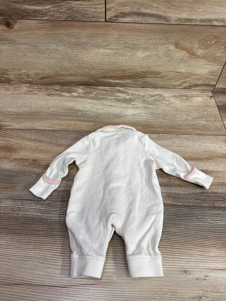 Back view of Amazon Essentials x Sofia Grainge ivory collared coverall with pink trim and cuffs on wood