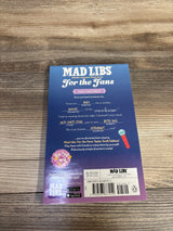 Top-down view of Mad Libs For the Fans: Taylor Swift Edition back cover showing filled-in prompts and barcode on wood table