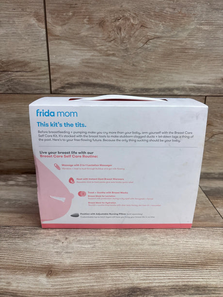 Front view of Frida Mom Breast Care Self Care Kit box with lactation tools and breast masks on wood floor