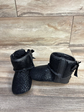 Pair of black textured baby booties with plush lining and back bows on wood floor