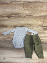 Flat lay of grey long-sleeve bodysuit and olive green pants set size 6M showing snap closures and drawstring on wood floor