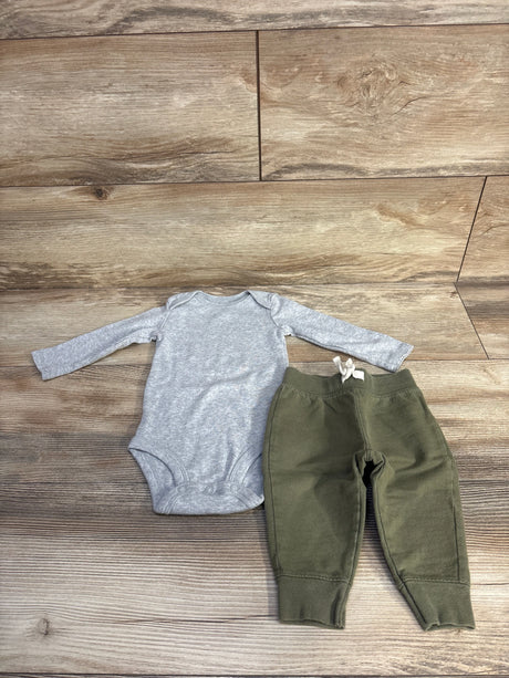 Flat lay of grey long-sleeve bodysuit and olive green pants set size 6M showing snap closures and drawstring on wood floor