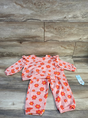 Flat lay of Cat & Jack 2T floral French terry set showing peach top with ruffle shoulders and matching pants on wood background