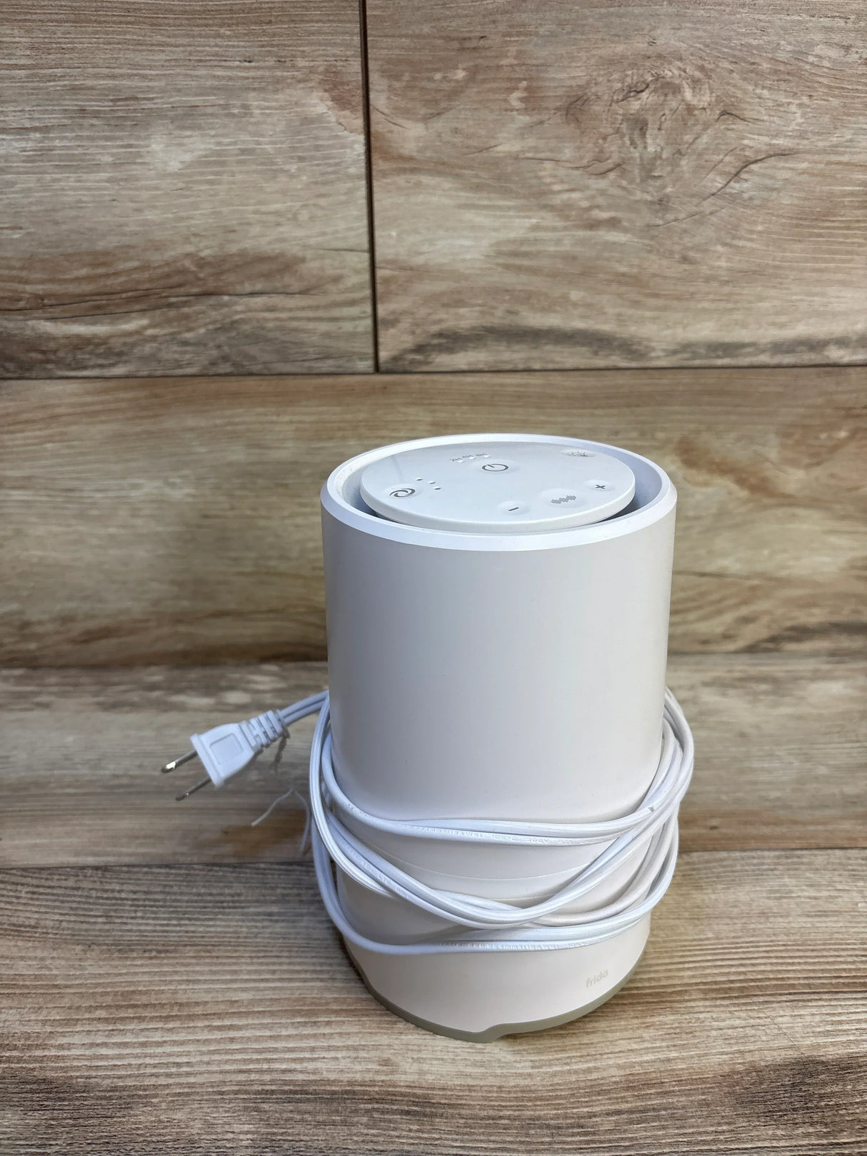 White Frida baby sound machine with power cord on wooden surface, nursery essential