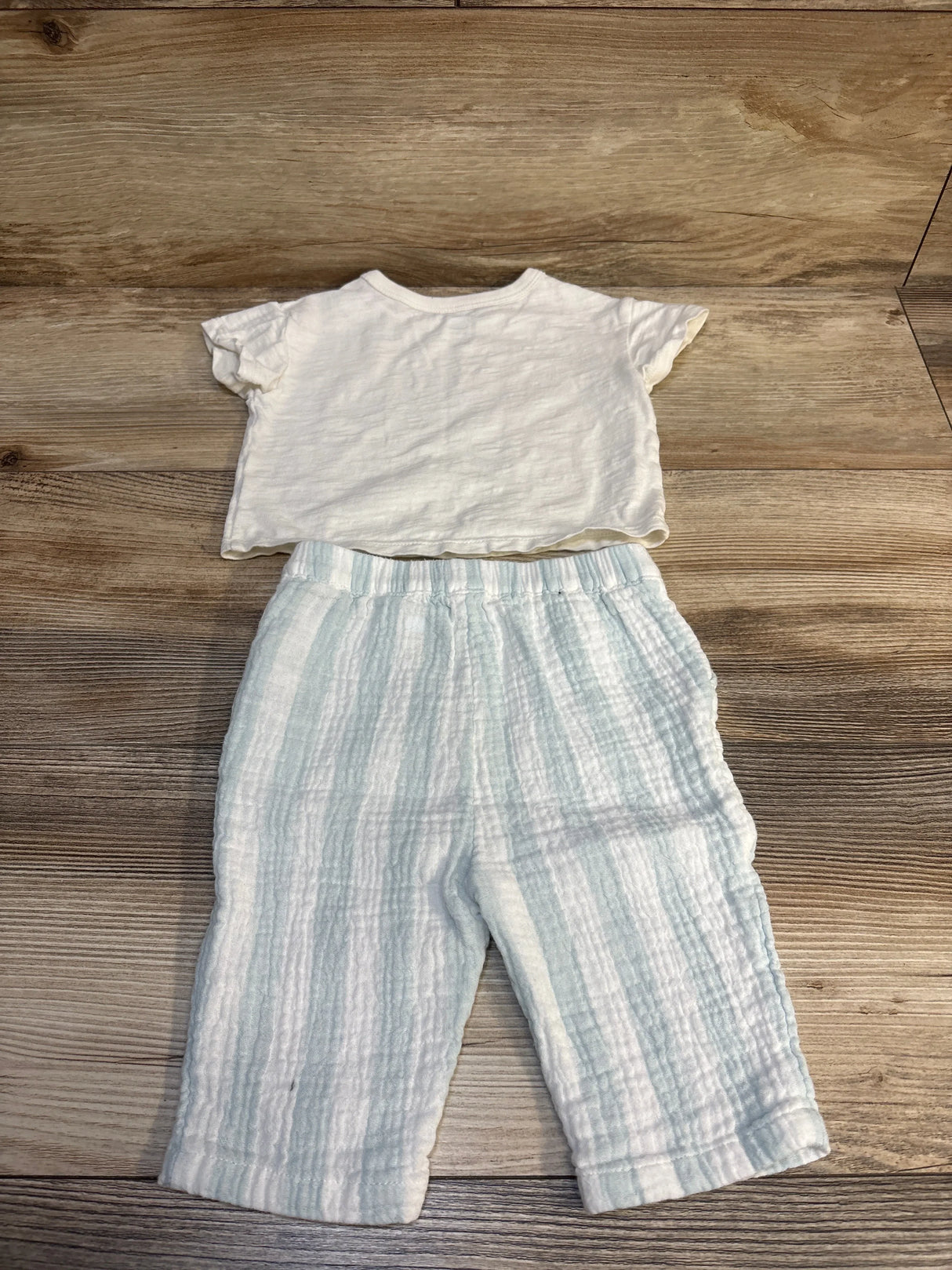 Baby outfit with short sleeve white shirt and light blue striped pants on wood floor