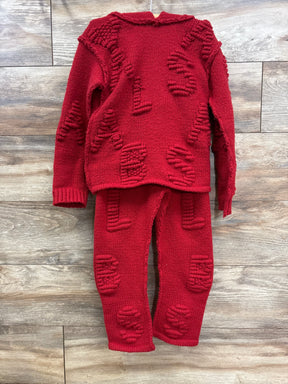 Red knit children's sweater and pants set with textured letter patterns, displayed on wood floor.