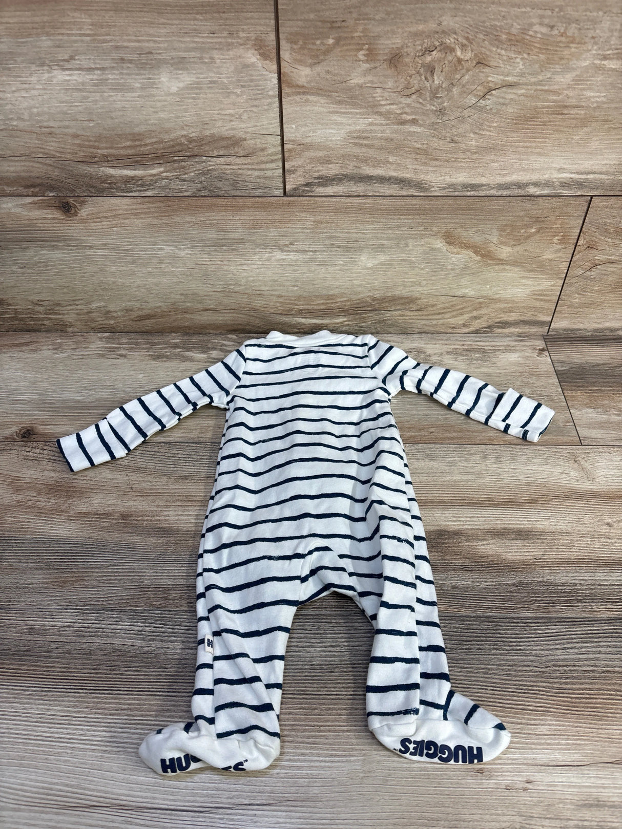 Flat lay of Huggies white and navy striped footed sleeper, 3 months, showing long sleeves and built in feet on wood floor