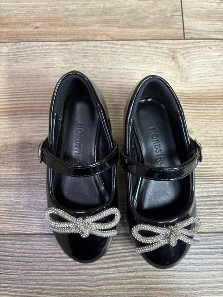 Top view of Nordstrom Lainee black Mary Jane flats, size 6C, showcasing jeweled bows on a wood-look background