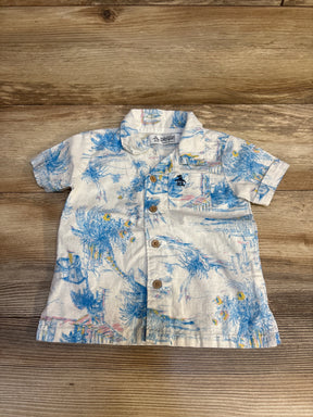 Toddler short sleeve button-up shirt with tropical blue palm print on wood background