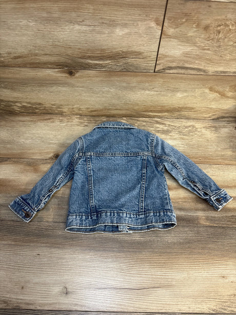 Children's denim jacket with long sleeves on a wood floor, gently used kids clothing