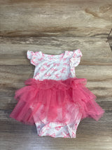 Flat lay of white newborn bodysuit dress with pink bow print and layered pink tulle tutu on wood background