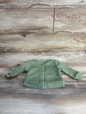 Green quilted baby jacket with zipper on wooden background