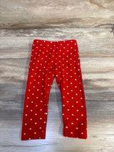 Red toddler leggings with white heart pattern on wooden background