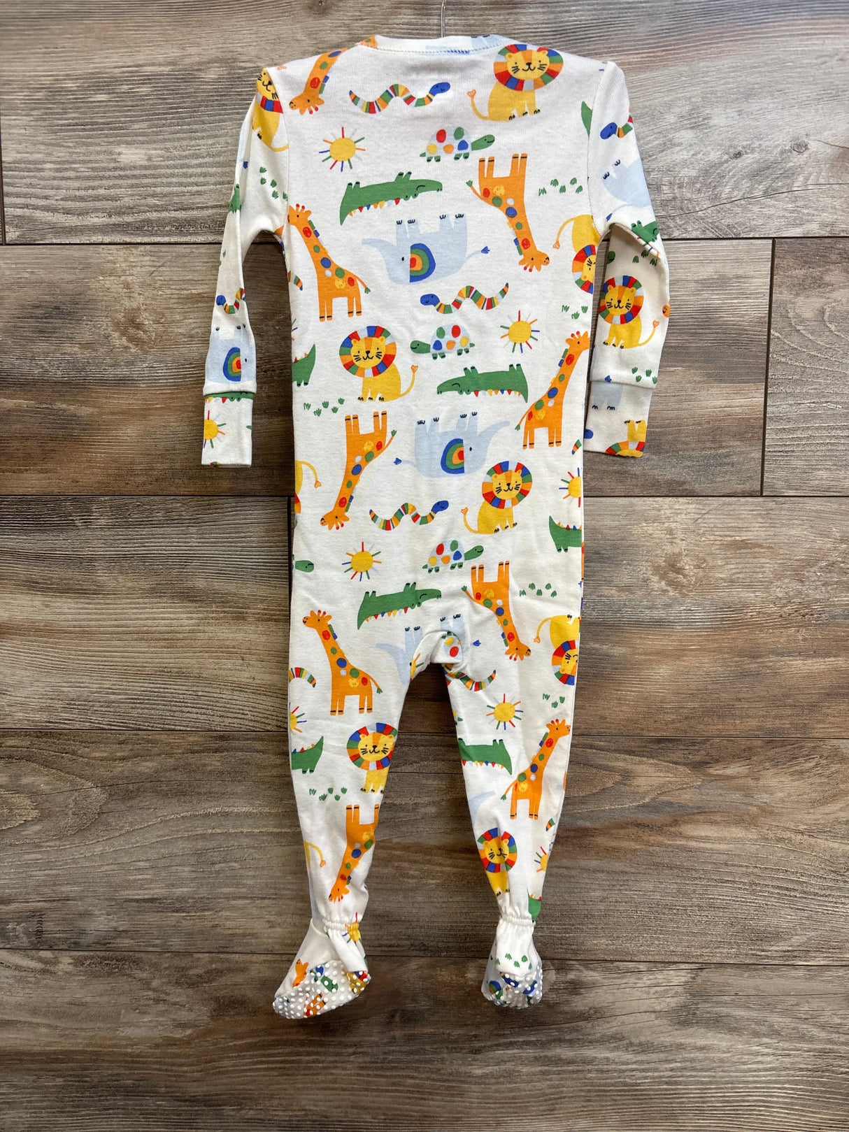 Back of Old Navy white footed sleeper with colorful animal print, non-skid grips on soles, size 12 to 18 months on wood floor