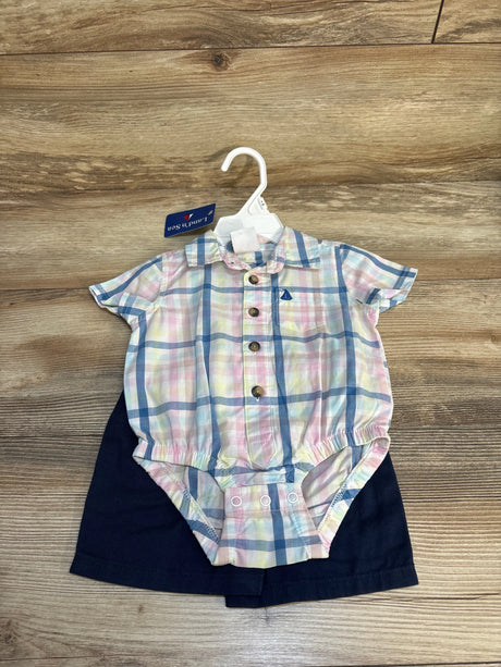 Pastel plaid baby romper with short sleeves and navy shorts on wooden background