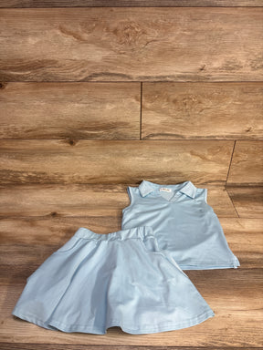 Flat lay of blue 2-piece girls' tennis outfit, collared sleeveless top and flared skirt with elastic waist on wood background