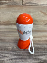 Front view of Baby Shusher sleep soother sound machine showcasing orange and white casing and attached white wrist strap on wood surface